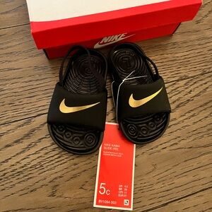 Size 5c (baby) Nike Kawa slide black and metallic gold NWT